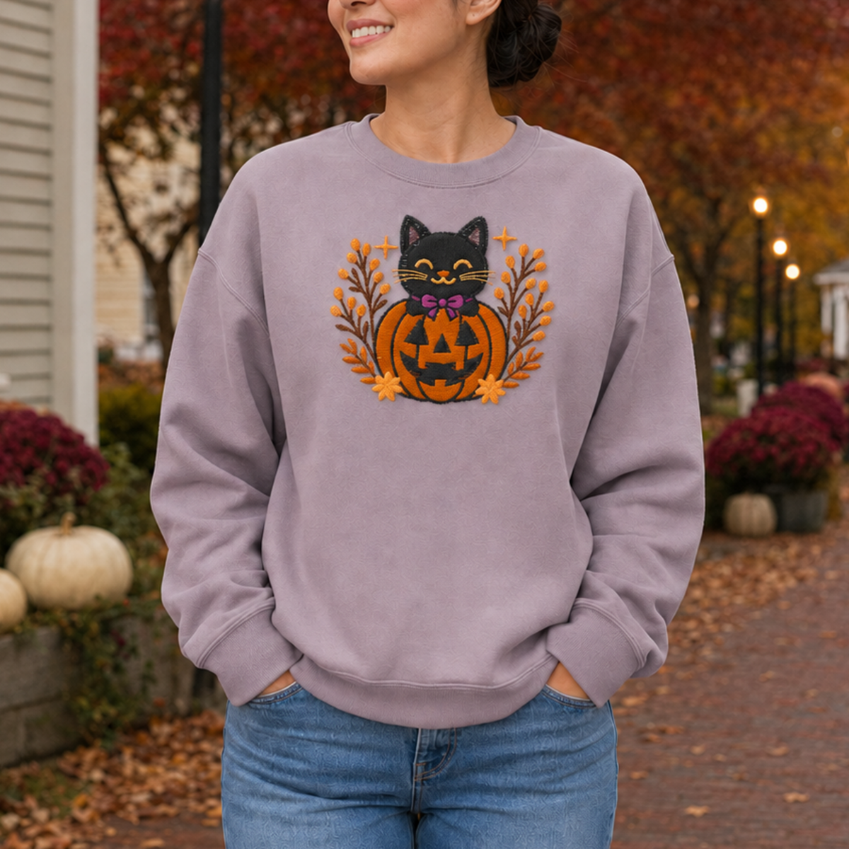 Detailed close-up of black cat and orange jack-o-lantern machine embroidery on a Paragon sweatshirt