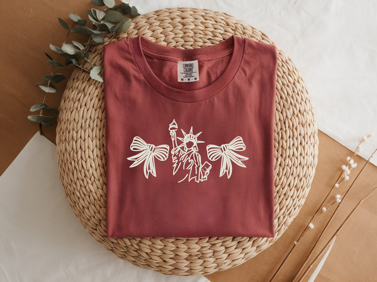 Red Comfort Colors shirt flat lay with a white Liberty and bows embroidery design