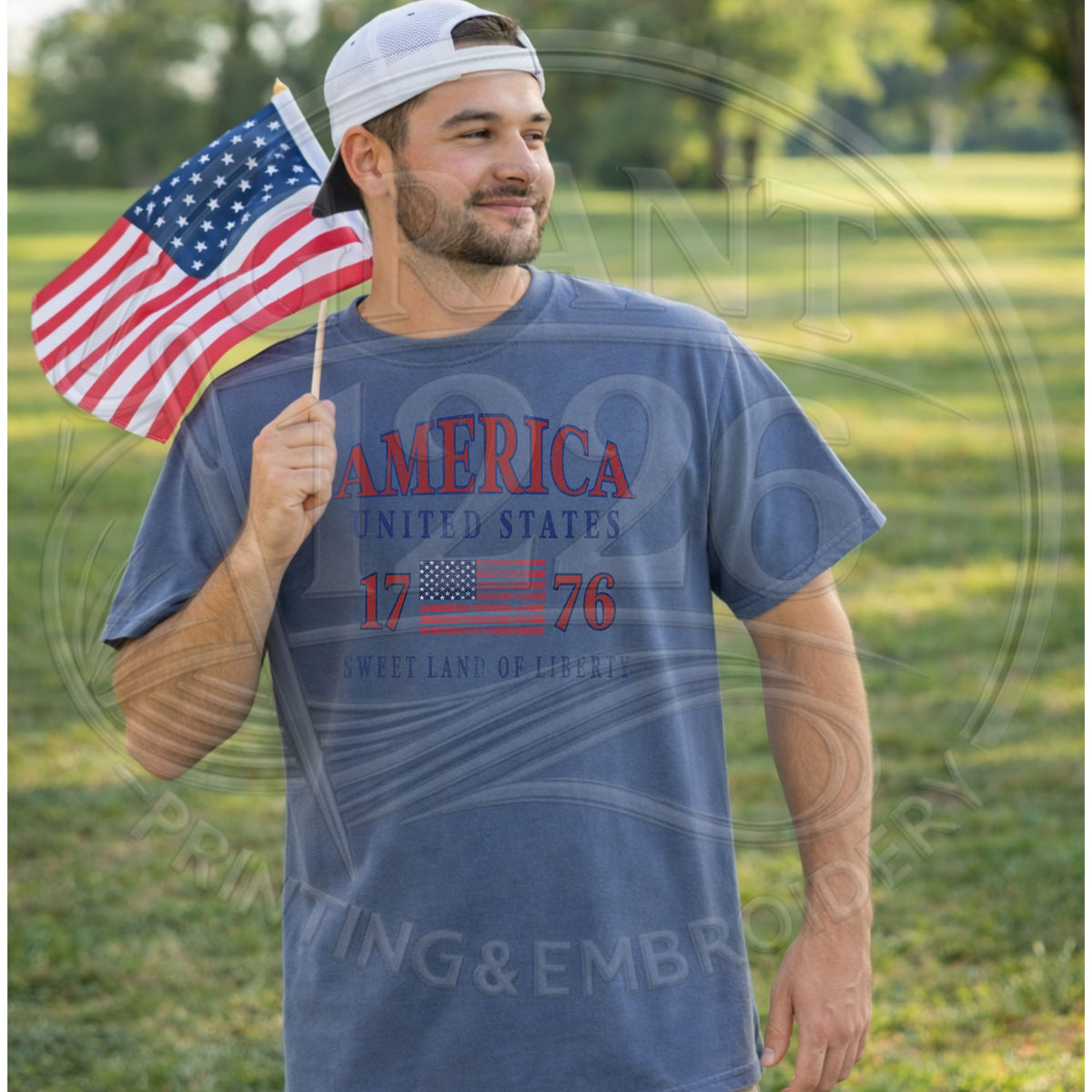Man wearing blue patriotic America United States 1776 graphic tee holding American flag