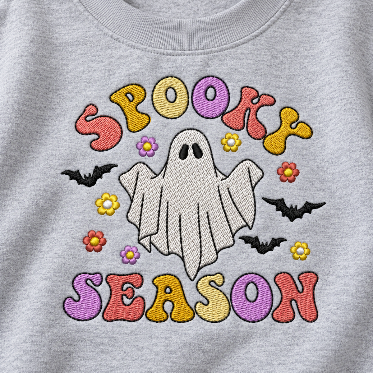 Close-up of pastel Spooky Season ghost machine embroidery and stitch detail on a Sport Grey sweatshirt