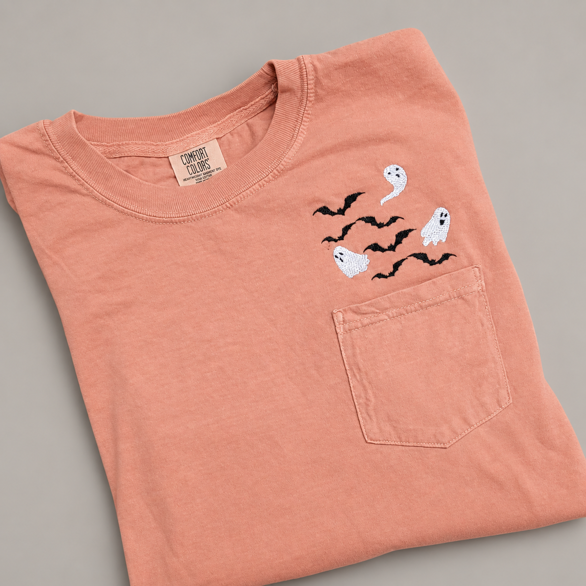 Terracotta Comfort Colors pocket T-shirt with three white embroidered ghosts and black bats above the left chest pocket