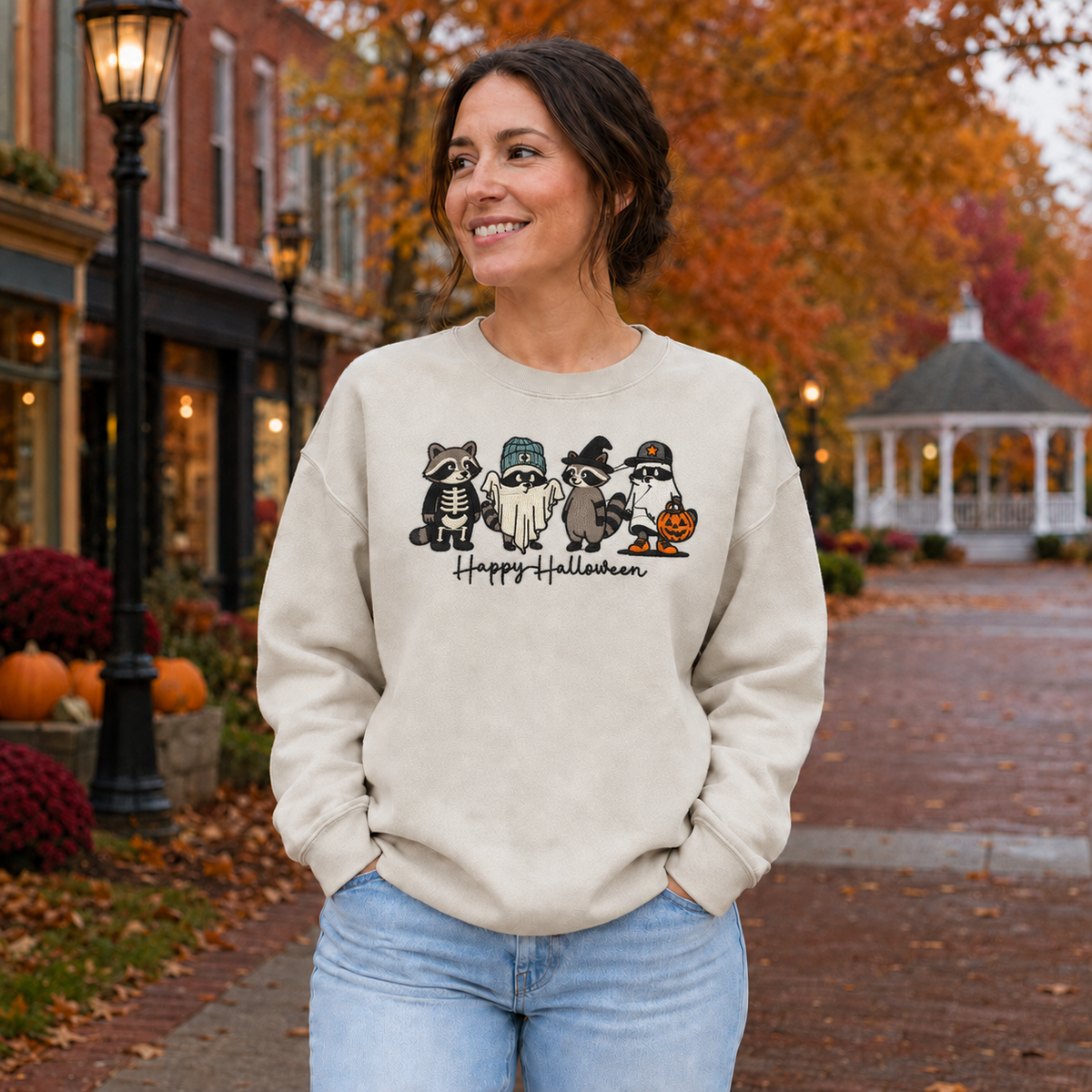 Woman wearing Sand embroidered Halloween raccoon sweatshirt with four costumed raccoons
