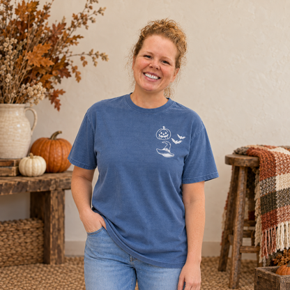 Woman wearing a Blue Jean garment-dyed T-shirt with white Halloween embroidery on the left chest.