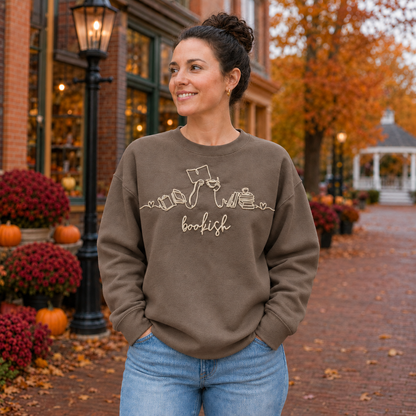 Bookish reader machine embroidery centered on a Brown Savanna Gildan Softstyle sweatshirt, approximately 10 inches wide