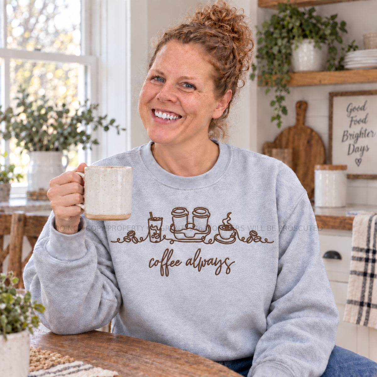 Ash Coffee Always embroidered sweatshirt modeled in a bright farmhouse kitchen with a coffee mug