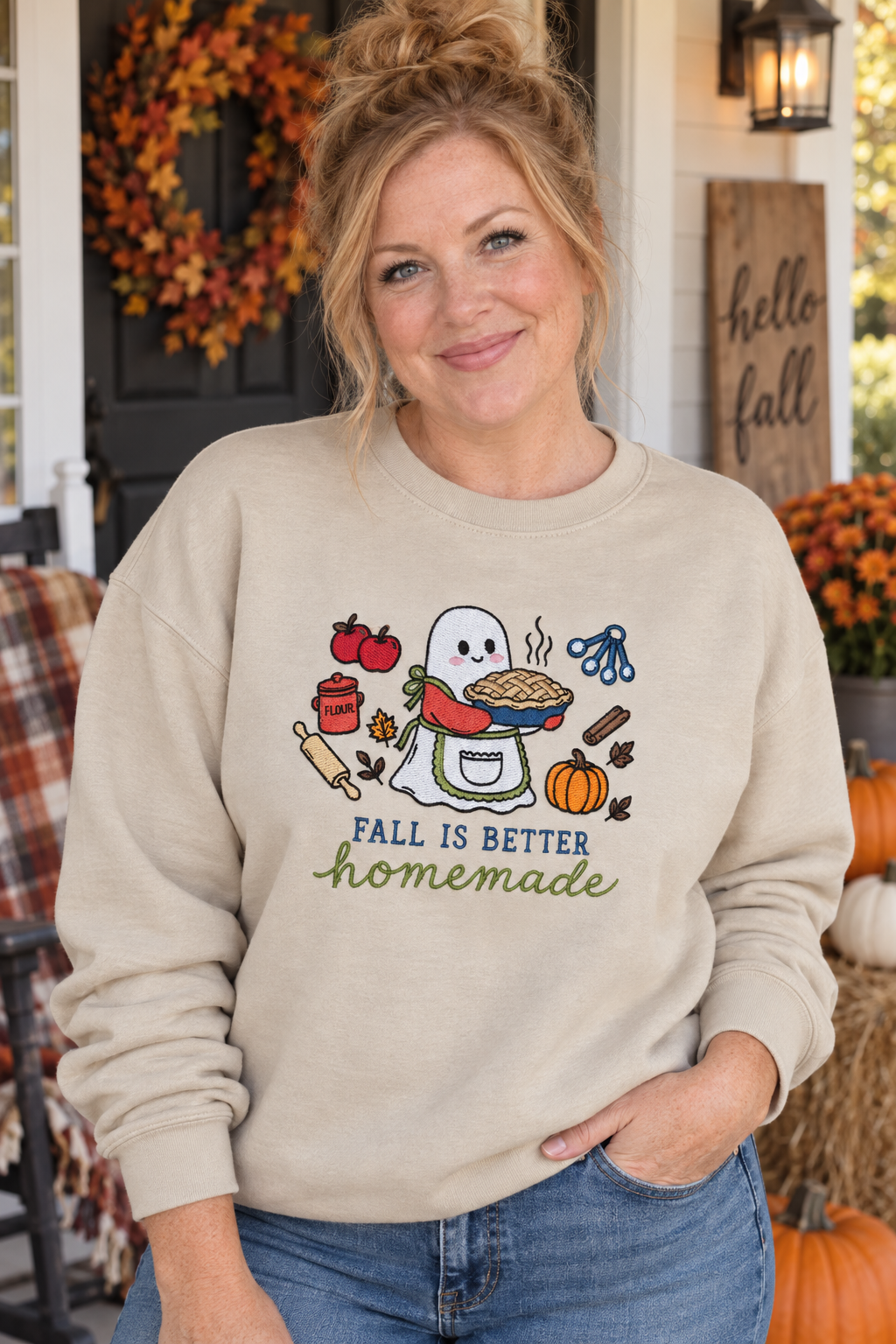 Woman wearing a Sand Fall Is Better Homemade embroidered ghost baker sweatshirt on a fall porch
