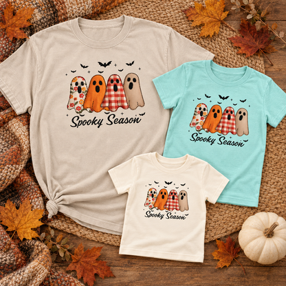 Adult, youth and toddler Spooky Season ghost shirts arranged in a fall flat lay to show coordinated family sizing.