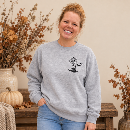 Woman wearing an Ash grey embroidered Halloween sweatshirt with a small black left-chest design.
