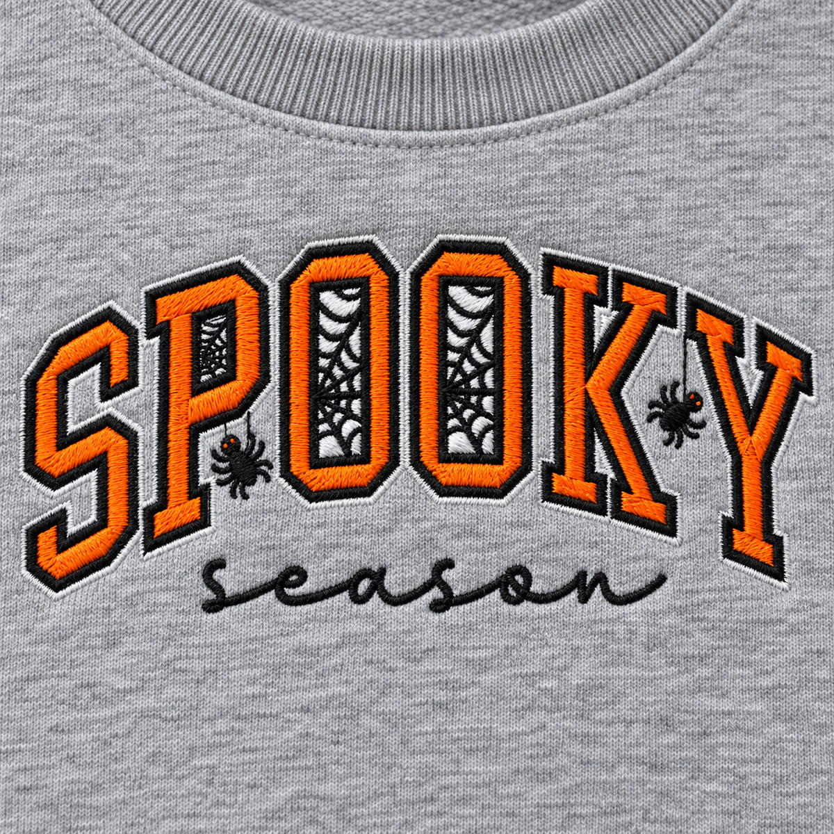 Close-up of orange black and white Spooky Season machine embroidery with spiderweb letters