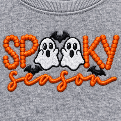 Close-up of orange, white and black Spooky Season ghost embroidery on a sport grey sweatshirt
