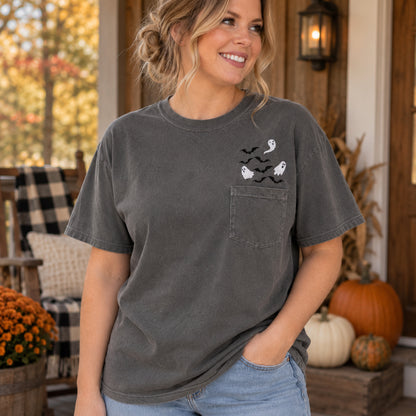 Woman wearing a Pepper Comfort Colors pocket T-shirt with white ghost and black bat embroidery above the chest pocket
