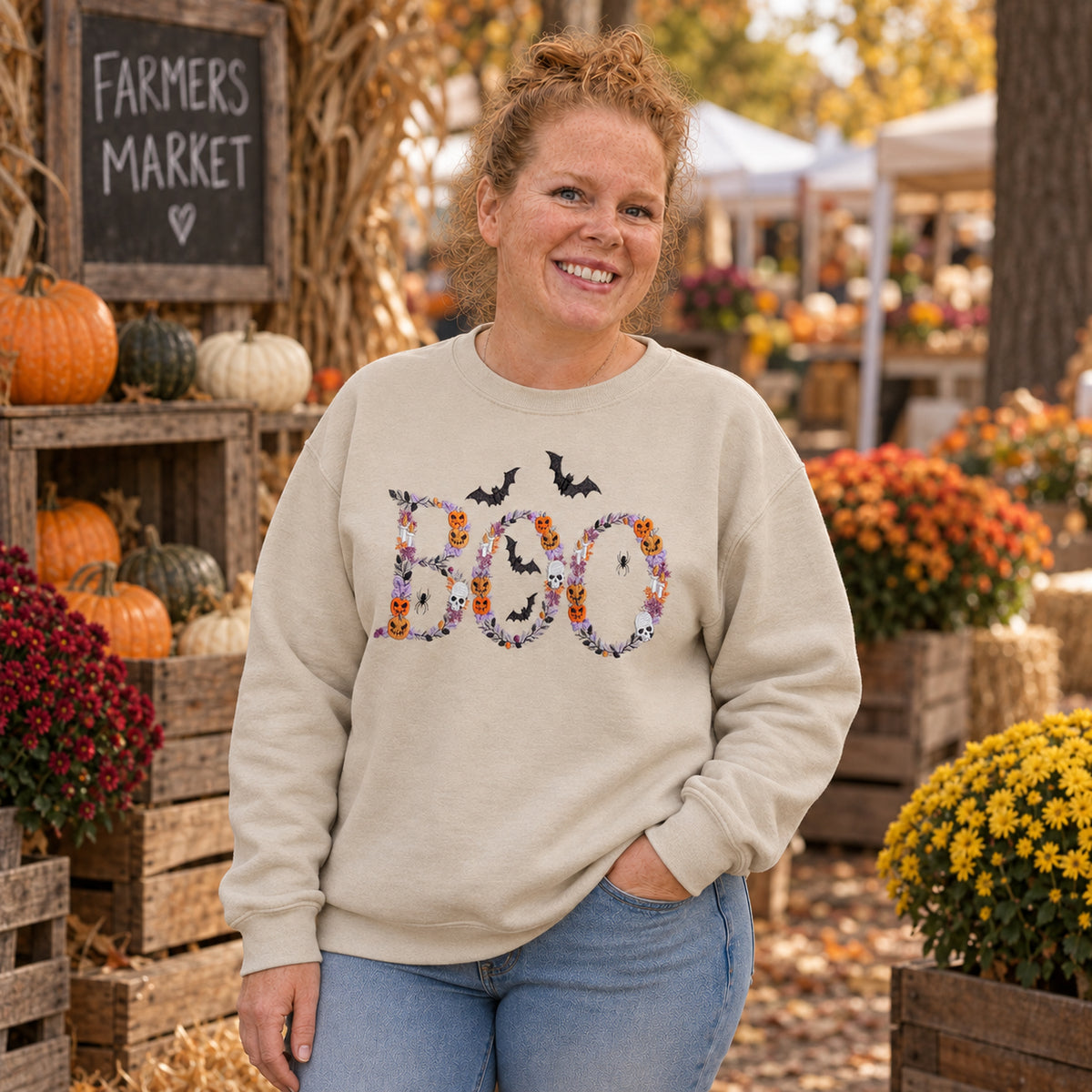 Woman wearing a Sand Botanical BOO embroidered crewneck at an outdoor fall farmers market