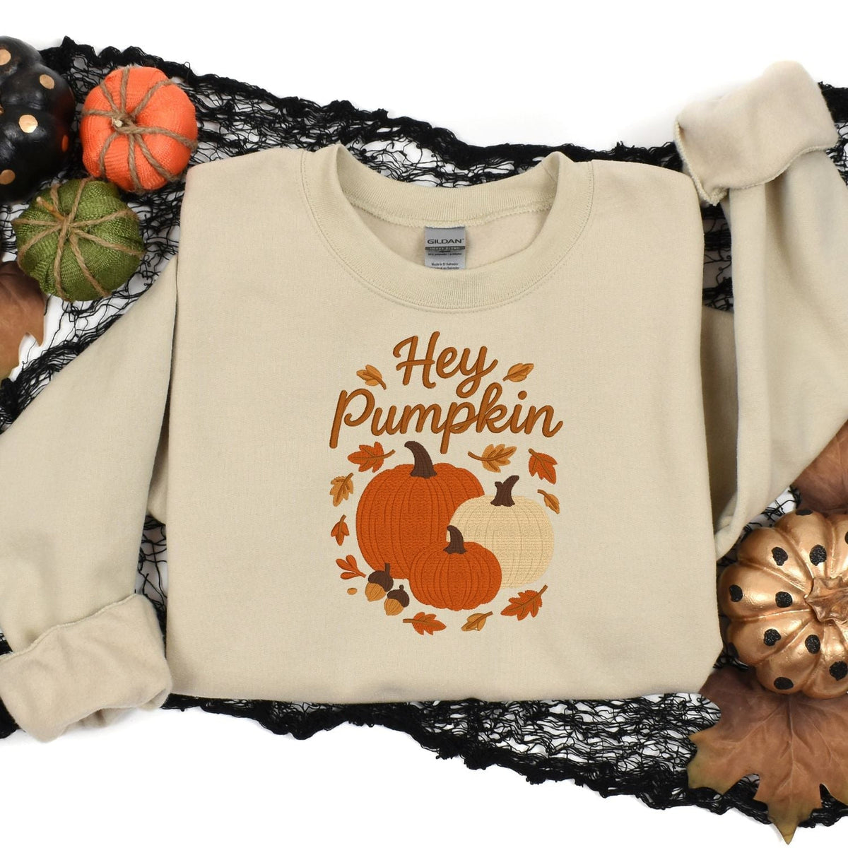 Sand Hey Pumpkin embroidered fall sweatshirt arranged with Halloween decorations