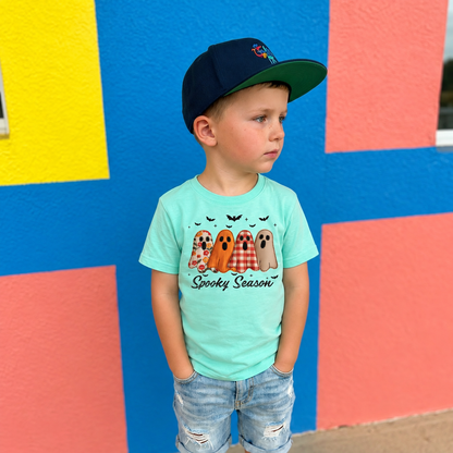 Child wearing a Saltwater LAT youth Spooky Season ghost T-shirt with a colorful patterned ghost design.