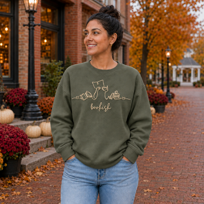 Bookish reader machine embroidery centered on a Military Green Gildan Softstyle sweatshirt, approximately 10 inches wide