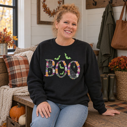 Woman wearing a Black Botanical BOO embroidered sweatshirt in a cozy fall entryway