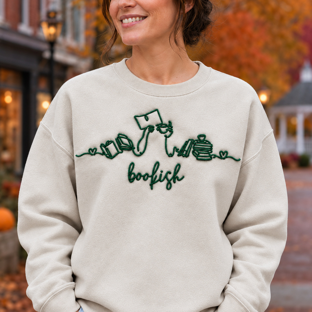 Close-up of forest green Bookish machine embroidery and stitch texture on a Sand sweatshirt