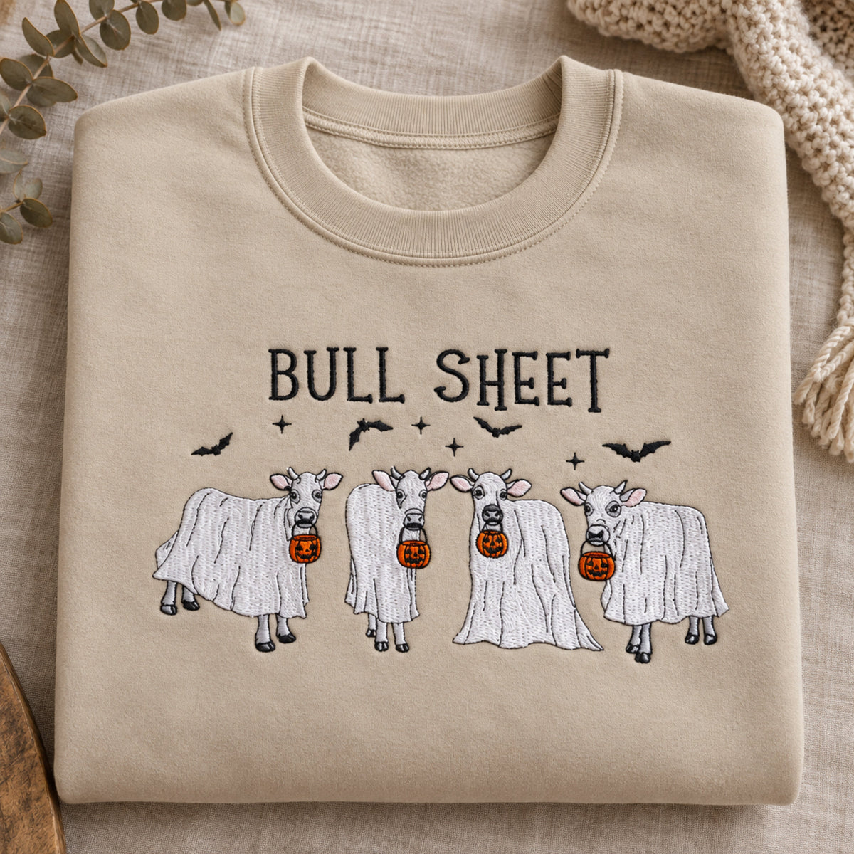 Close view of Bull Sheet cow ghost embroidery on a Sand sweatshirt