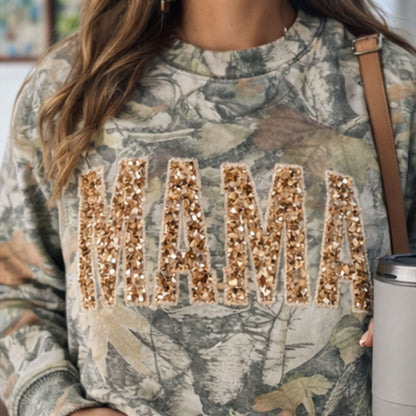 Camouflage sweatshirt with 'MAMA' in gold sequins worn by a person.