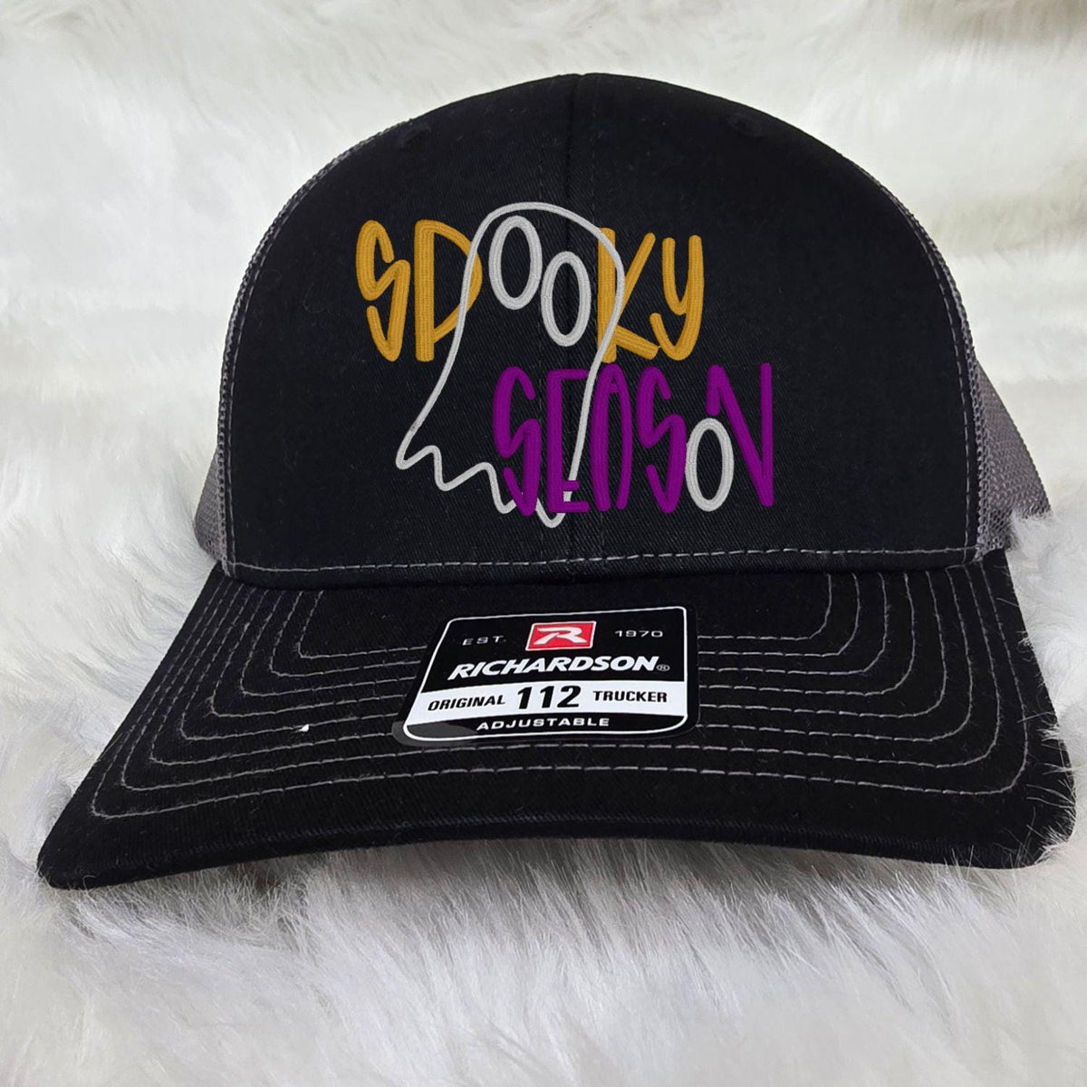 Black and charcoal adjustable trucker hat embroidered with a Spooky Season ghost