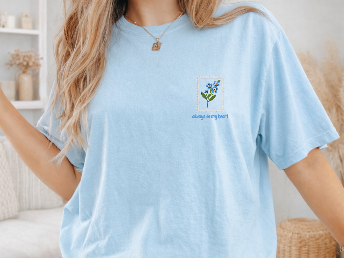 Close-up of embroidered blue forget-me-not flowers and Always in My Heart text on Chambray shirt