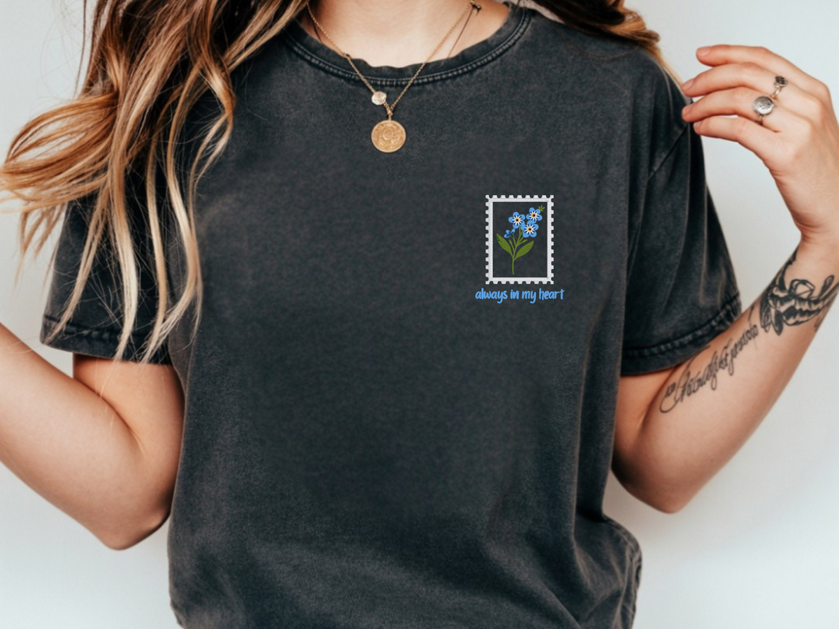 Close-up of embroidered blue forget-me-not flowers and Always in My Heart text on Pepper short sleeve shirt