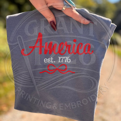 Blue patriotic America Est 1776 shirt flat lay outdoors