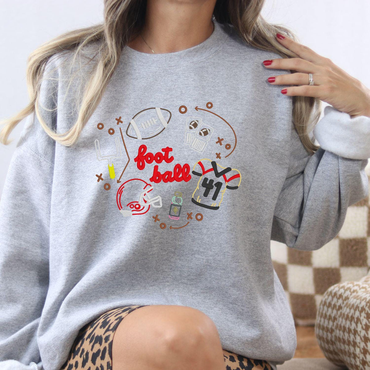 Ash embroidered football crewneck with colorful game day equipment design
