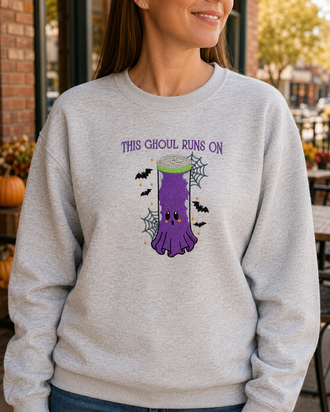 Ash This Ghoul Runs On embroidered sweatshirt in a fall coffee shop setting