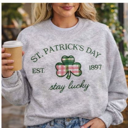Person wearing a St. Patrick's Day sweatshirt with a shamrock design and text, holding a coffee cup.