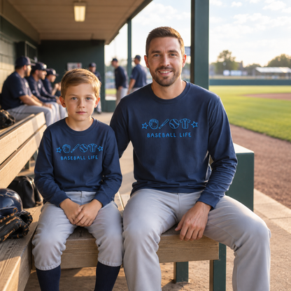Father and child wearing matching navy Baseball Life embroidered shirts beside a baseball field