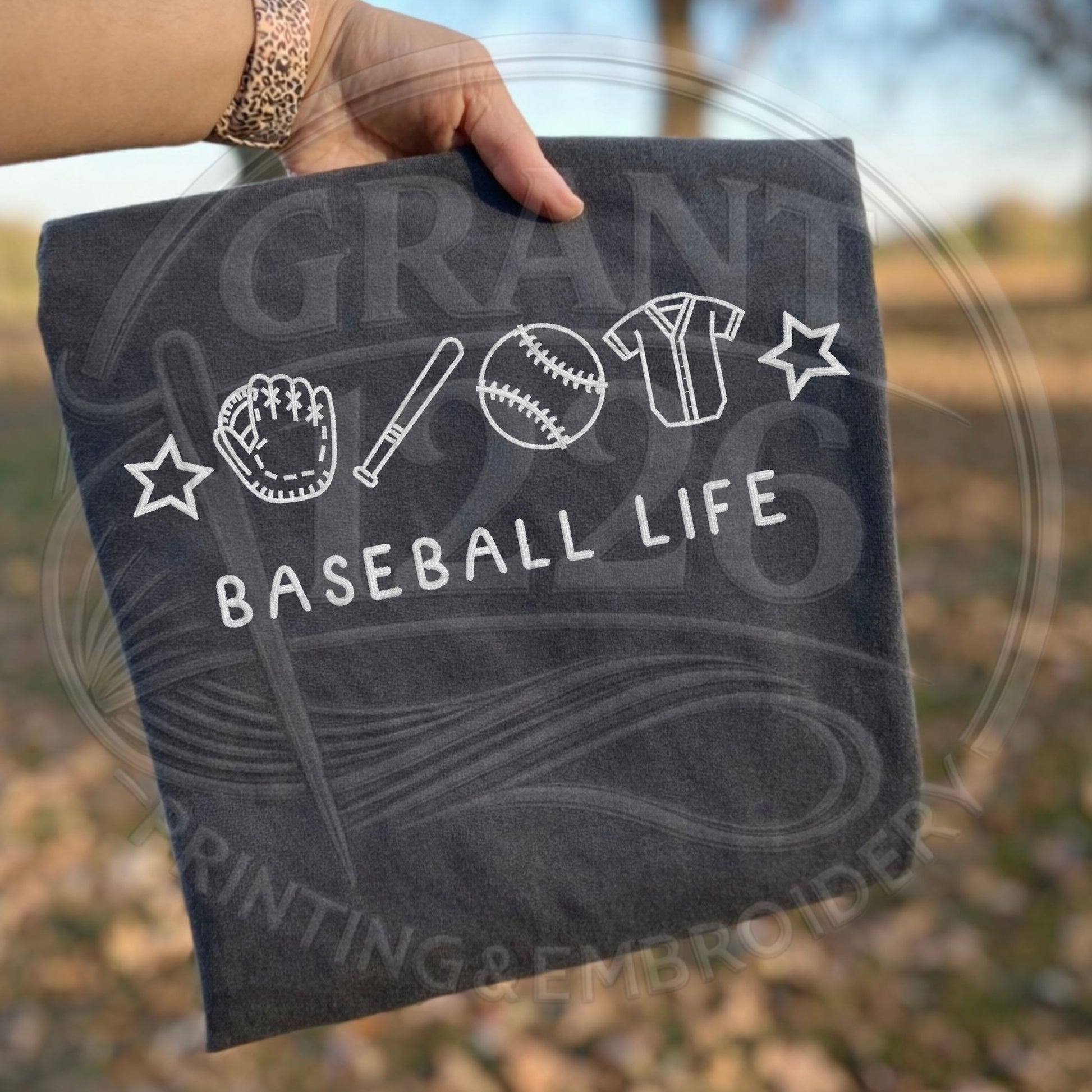 Folded embroidered baseball life shirt on dark gray Comfort Colors tee