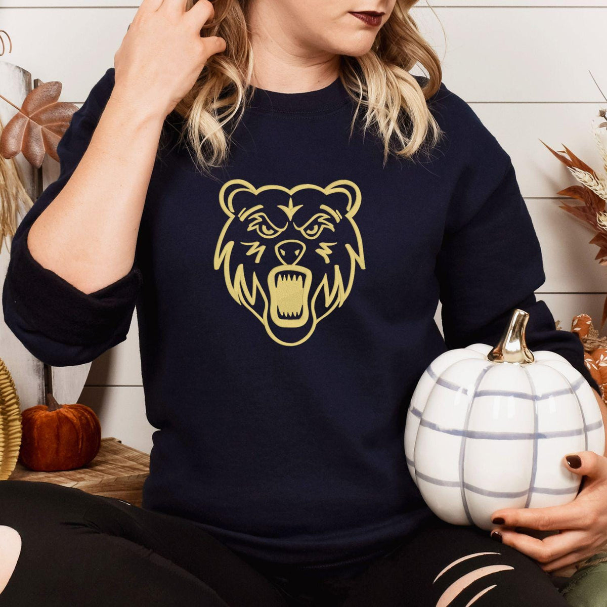Navy bear mascot embroidered sweatshirt modeled while holding a white pumpkin