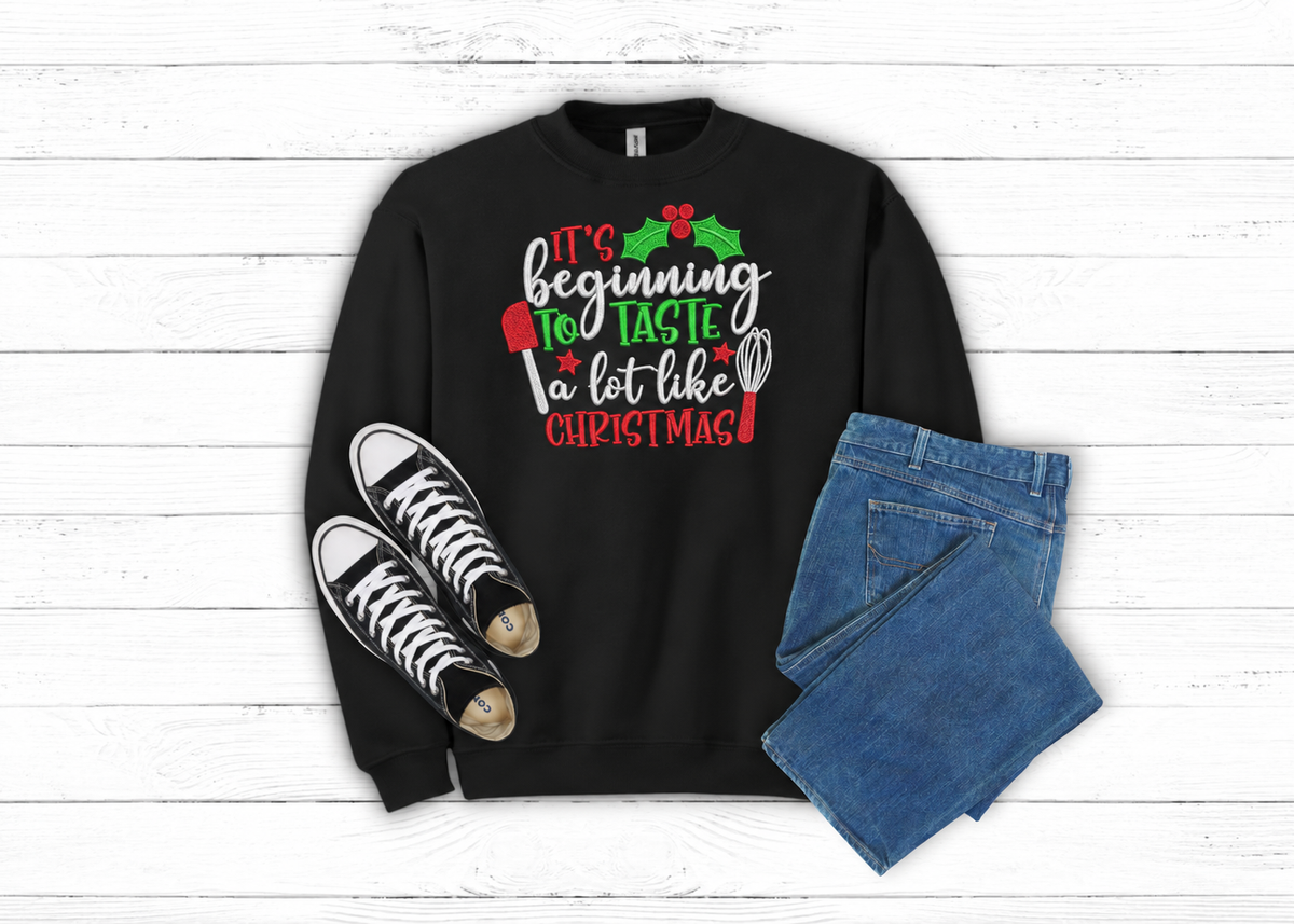 Black Beginning to Taste Like Christmas embroidered Gildan sweatshirt flat lay