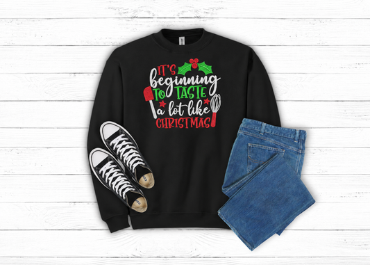 Black Beginning to Taste Like Christmas embroidered Gildan sweatshirt flat lay
