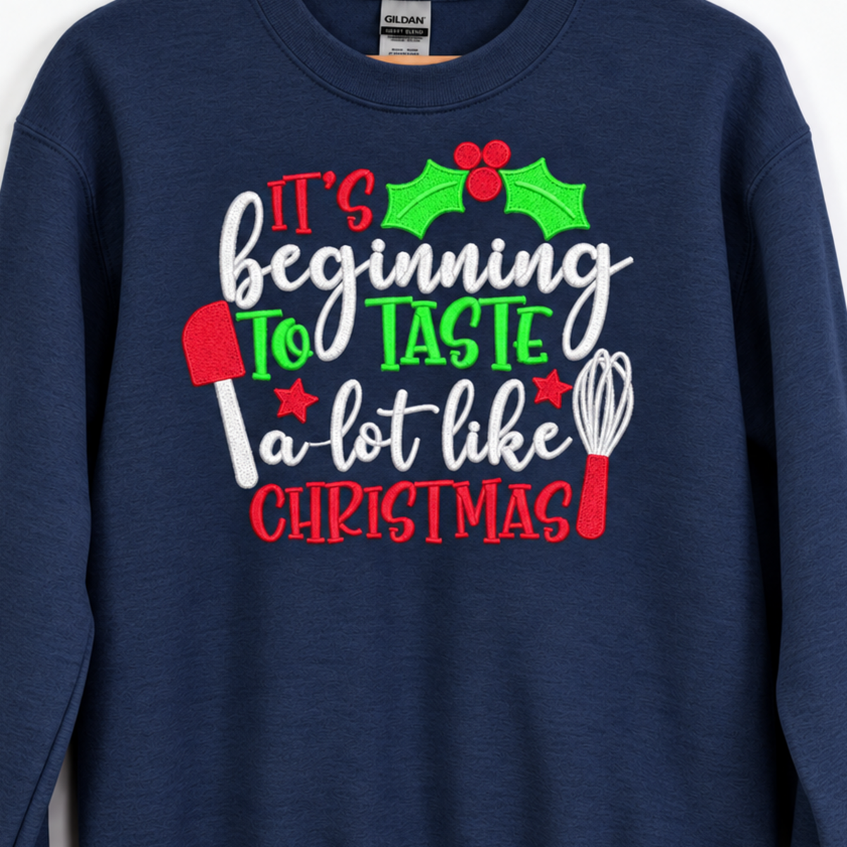 Close-up of holiday baking embroidery with whisk and spatula on navy sweatshirt