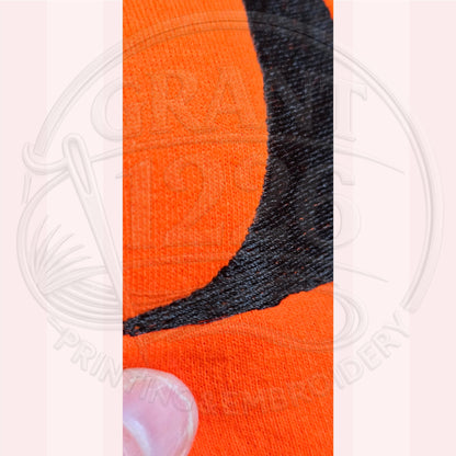 Close-up of black machine embroidery on orange Halloween witch sweatshirt