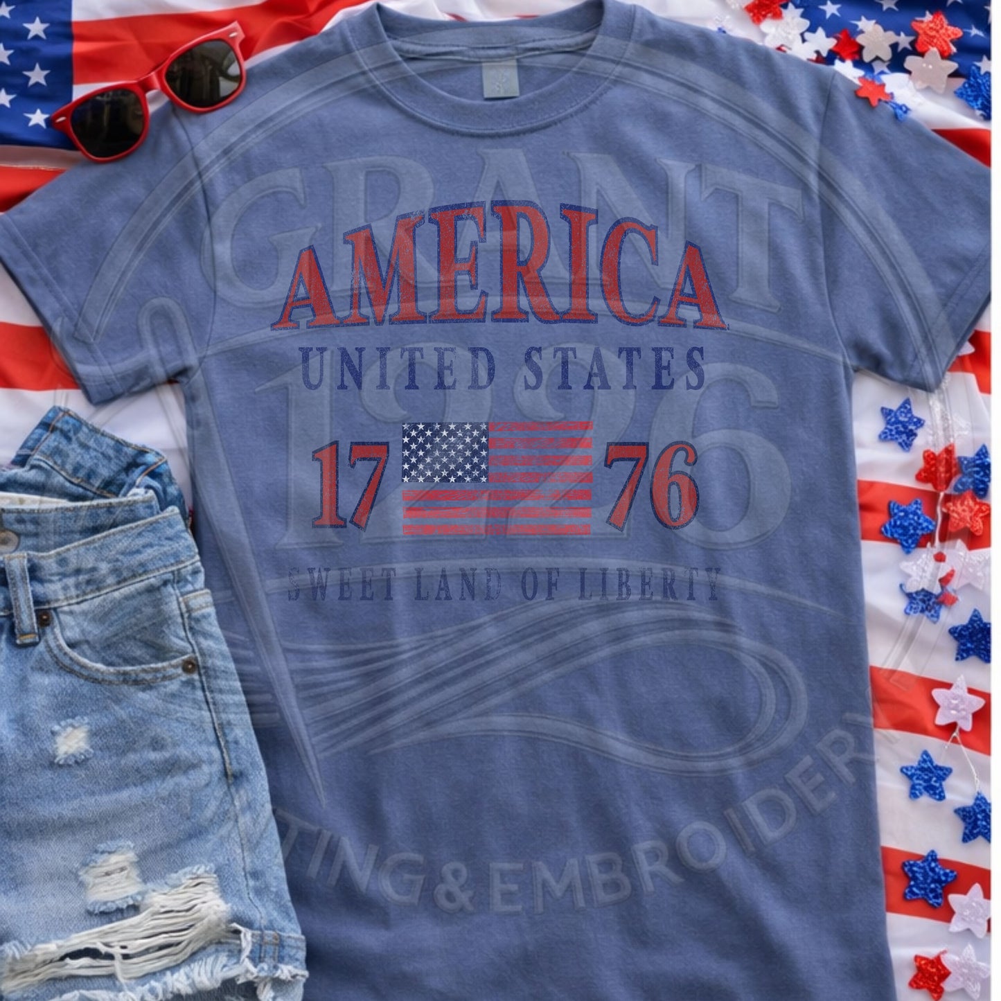 Blue patriotic America 1776 Comfort Colors shirt flat lay with Fourth of July accessories