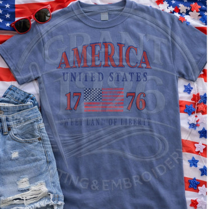 Blue patriotic America 1776 Comfort Colors shirt flat lay with Fourth of July accessories