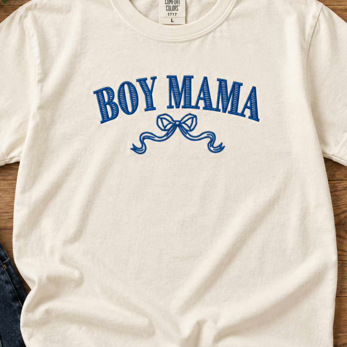 Close-up of blue Boy Mama bow embroidery on Ivory shirt