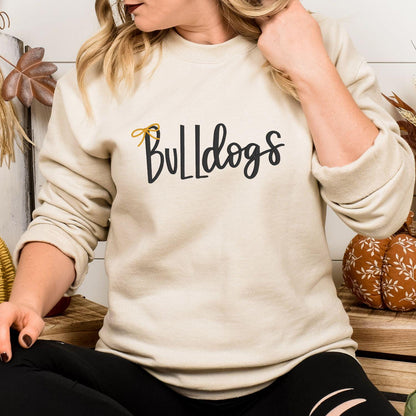 Sand Bulldogs script and bow embroidered sweatshirt modeled indoors