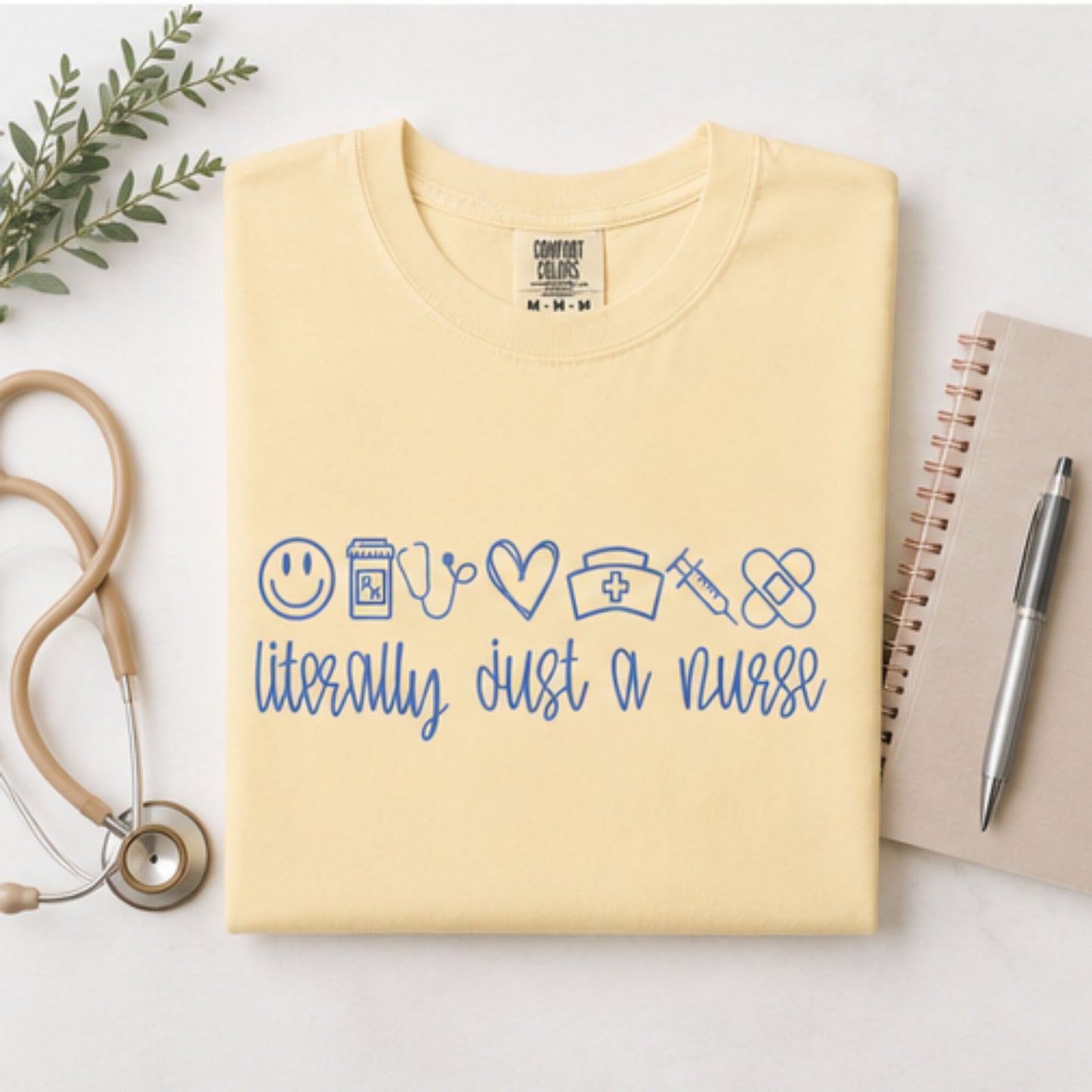 Embroidered Comfort Colors butter short sleeve nursing t-shirt with blue thread lettering flat lay