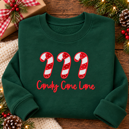 Forest Green Candy Cane Lane embroidered sweatshirt folded beside Christmas gift