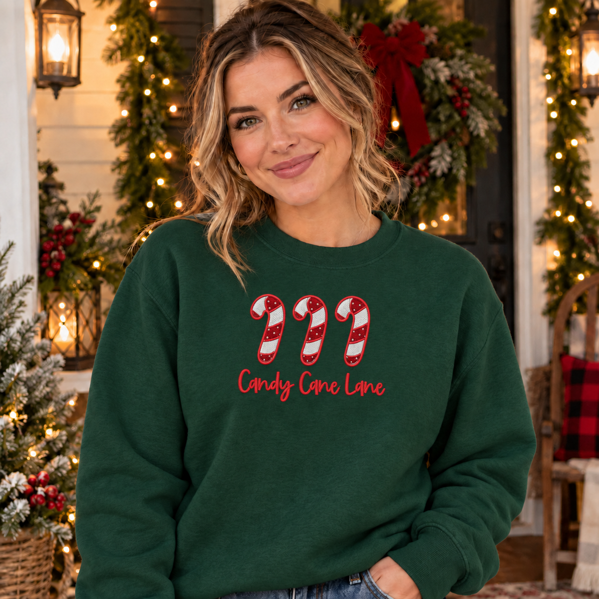 Adult wearing Forest Green Candy Cane Lane embroidered sweatshirt on Christmas porch