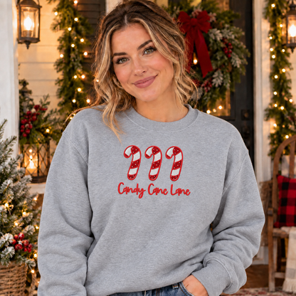 Adult wearing Sport Grey Candy Cane Lane embroidered sweatshirt on Christmas porch