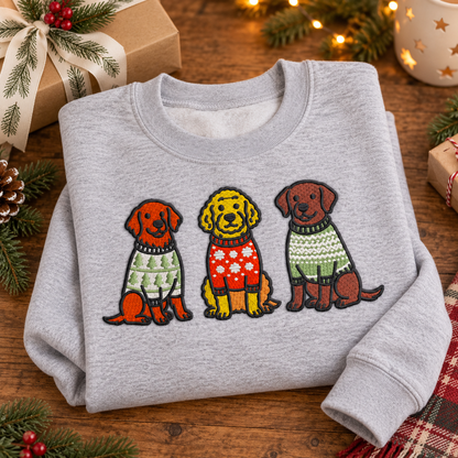 Folded heather grey Christmas dog embroidered sweatshirt styled with evergreen and a gift box