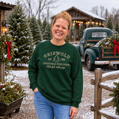 Forest green embroidered Christmas tree farm sweatshirt shown outdoors at a snowy tree farm
