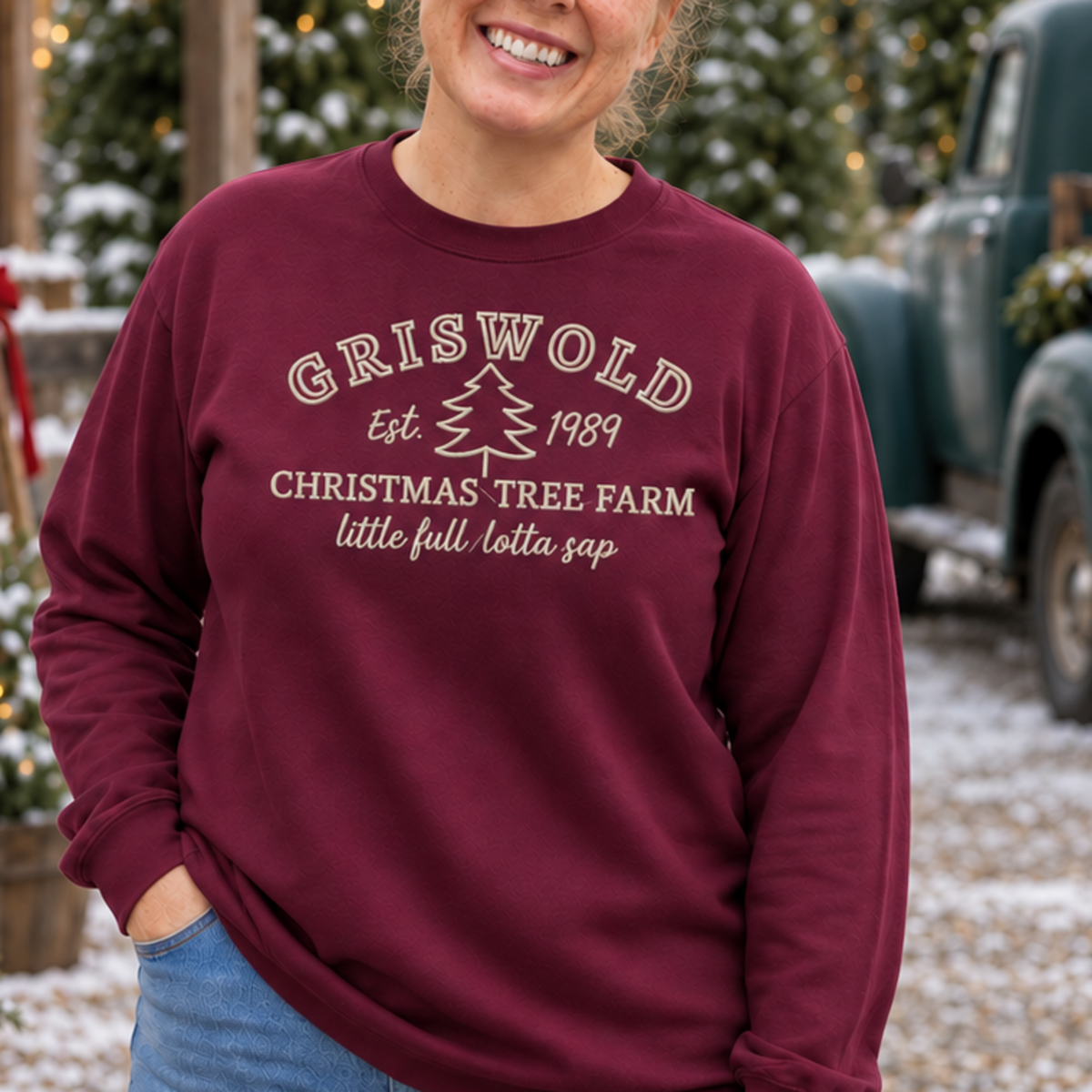 Close view of cream holiday tree farm embroidery on a maroon crewneck sweatshirt