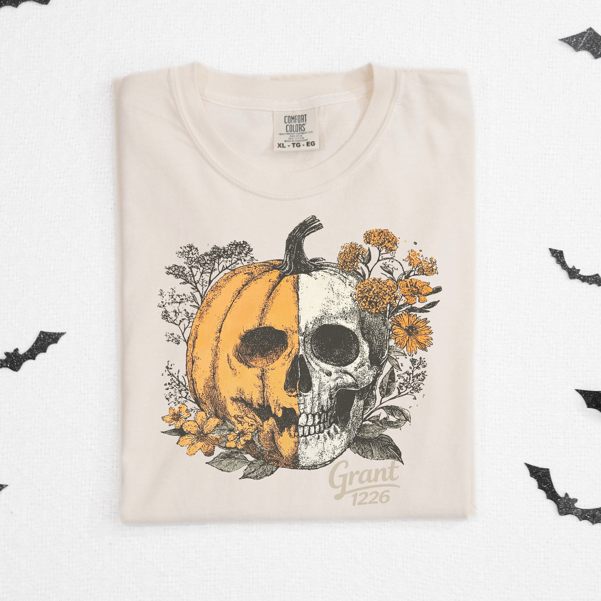 Comfort Colors Ivory shirt flat lay with floral pumpkin skull design and bat accents