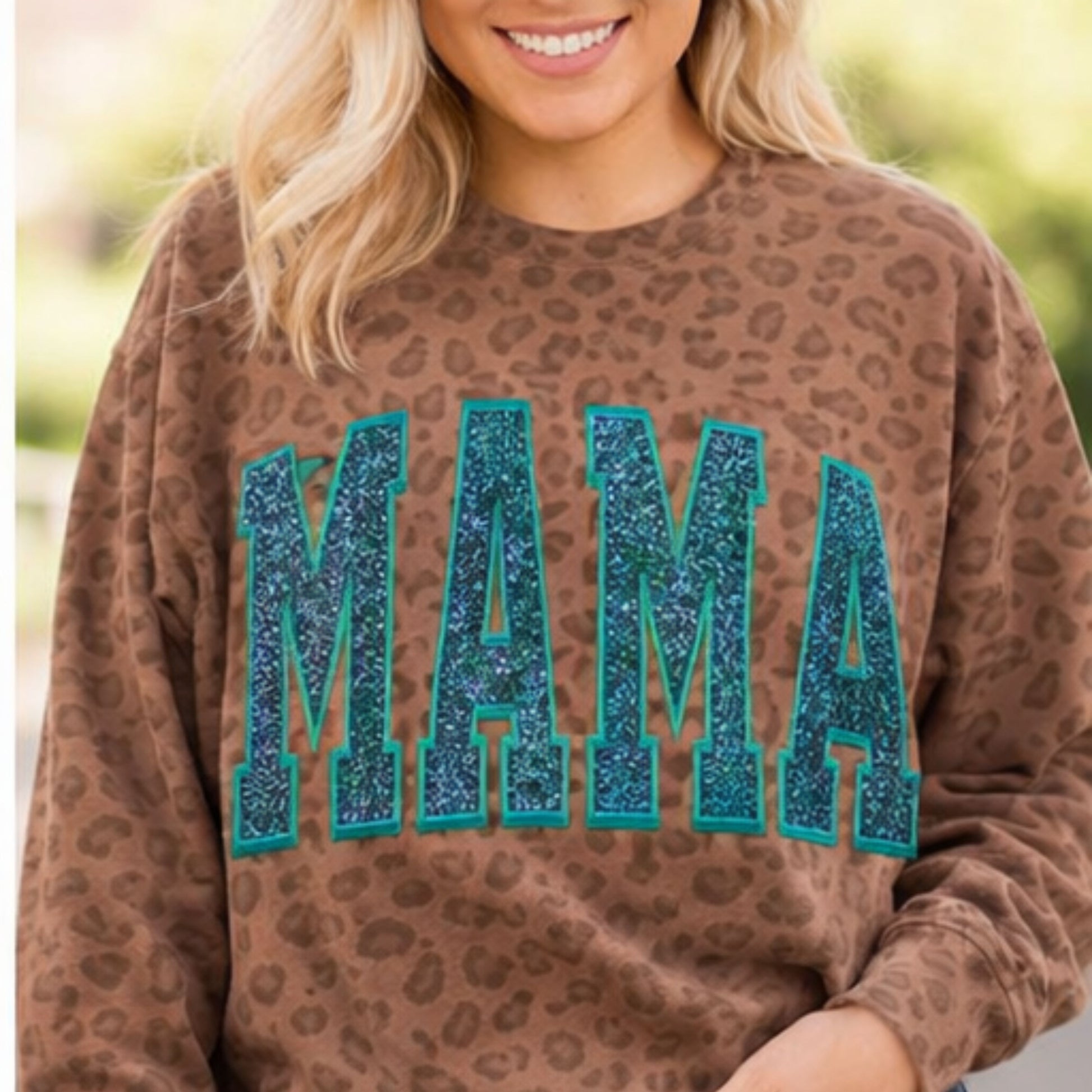 Person wearing a brown leopard print sweatshirt with 'MAMA' in blue glitter letters.